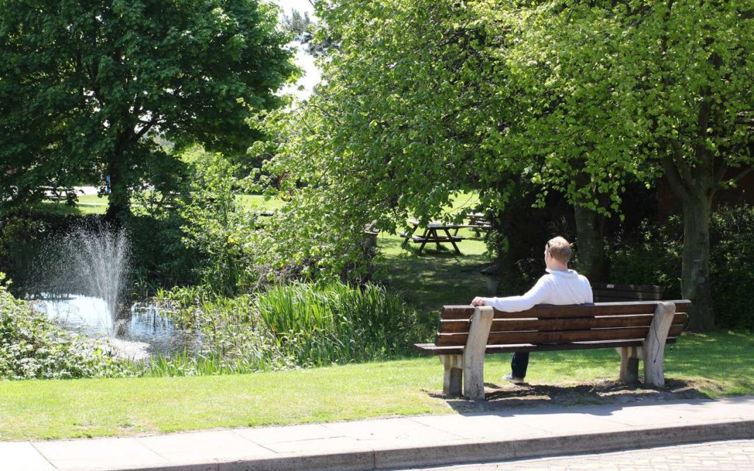 office-worker-sat-on-bench-by-pond